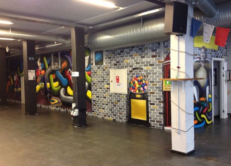 Urban interior featuring colorful street art graffiti on brick walls and a gumball machine mural.