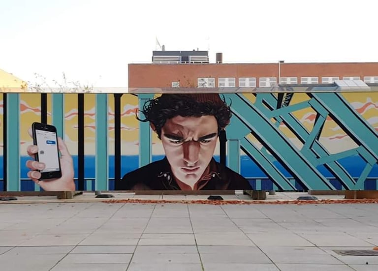 Urban street art mural depicting a man looking at a smartphone against a colorful geometric background.
