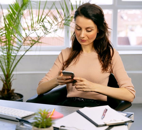 mujer enviando mensaje de texto desde la oficina