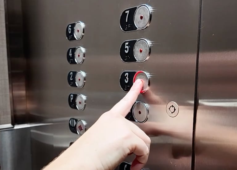 a hand pressing the 3rd floor button on a control operating panel inside an elevator