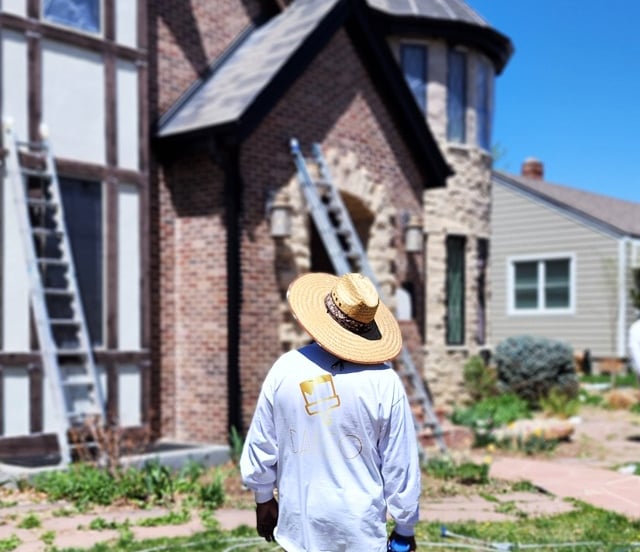 a man in a straw hat painting exterior wearing daeco paintng shirt