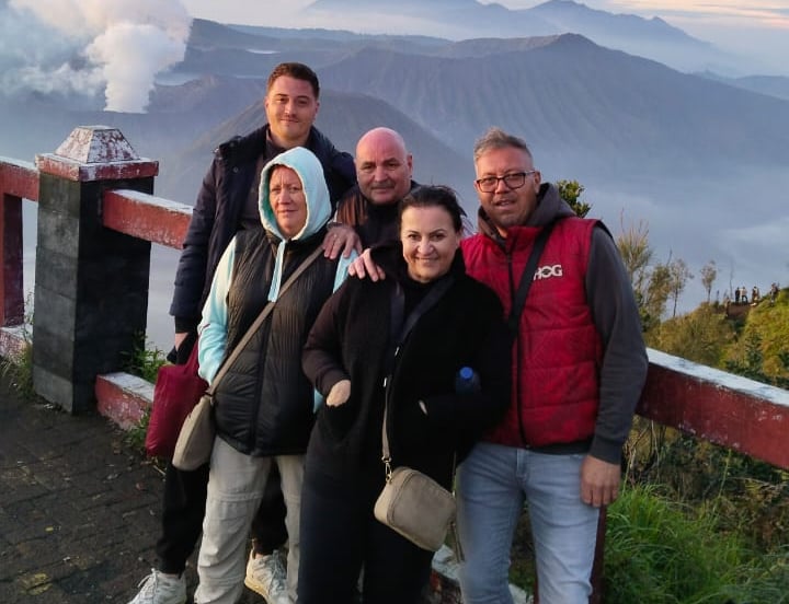Sekeluarga tourism dari Belanda sedang berpose dengan latar belakang gunung Bromo.