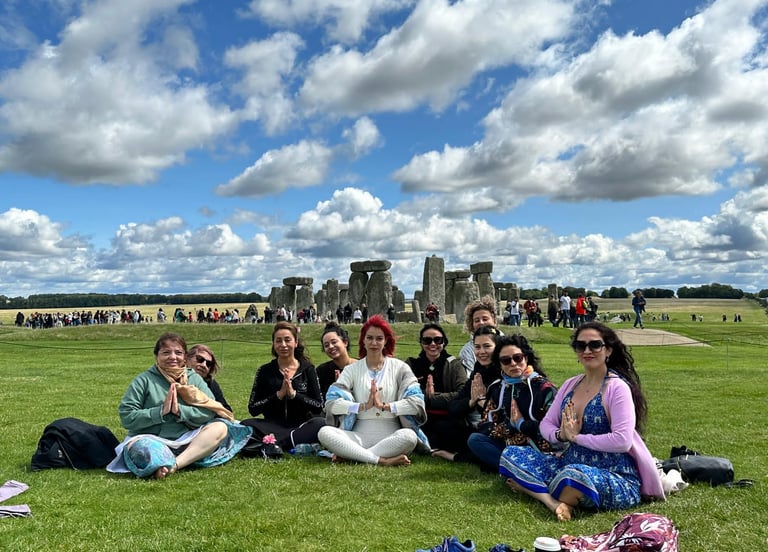 Grupo de mujeres en pose de meditación cerca Stonehenge