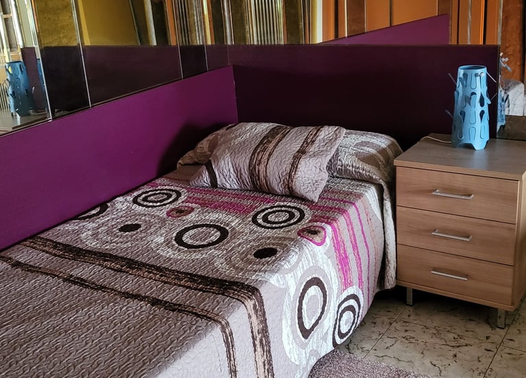 Cama y espejo de la habitación