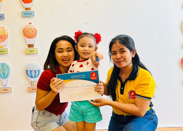 Young student holding a certificate of completion at a daycare graduation ceremony with teachers.