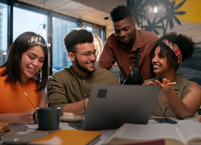 Groupe de jeunes étudiants devant un ordinateurs et des cahiers et livres