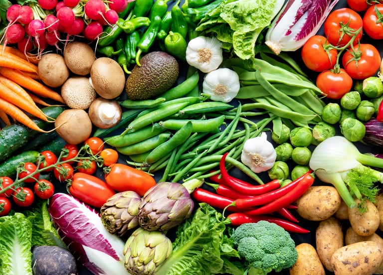 Wide overhead banner of fresh organic vegetables including kale, carrots, tomatoes, and broccoli.