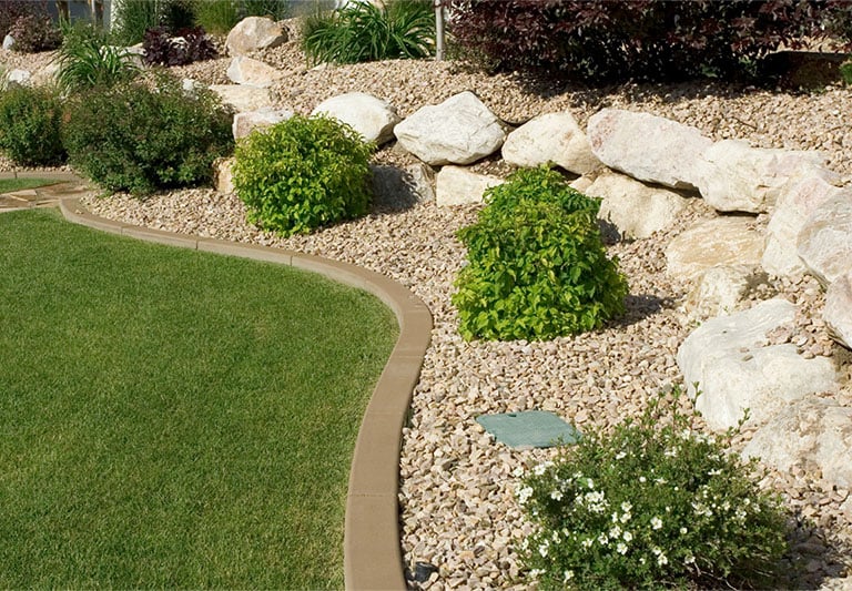 Landscape gravel bed on a hillside with large decorative rocks and low-maintenance plants
