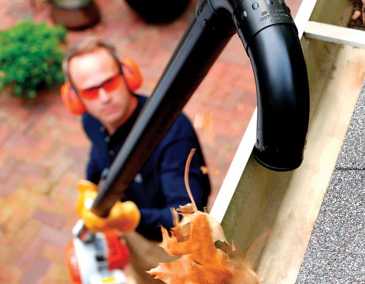 Professional gutter cleaning technician working on a residential home