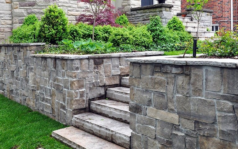 Natural stone retaining wall with integrated steps and garden beds.