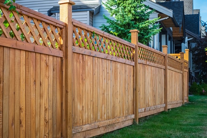 Classic wood privacy fence featuring a decorative lattice top and sturdy cedar posts.