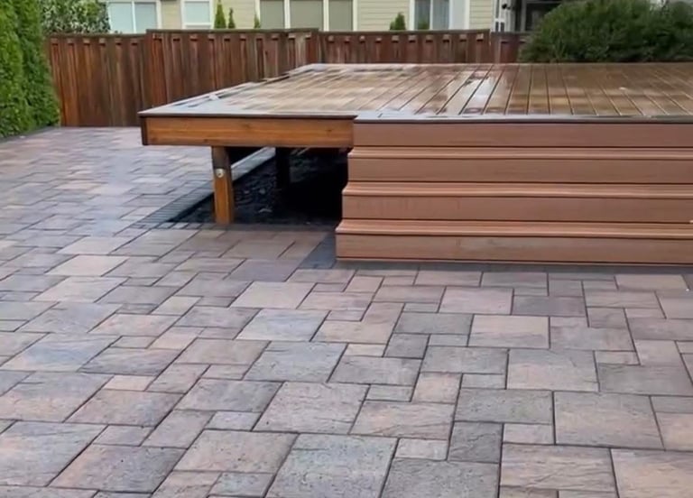 Custom multi-level wooden deck integrated with a modern interlocking stone patio base.