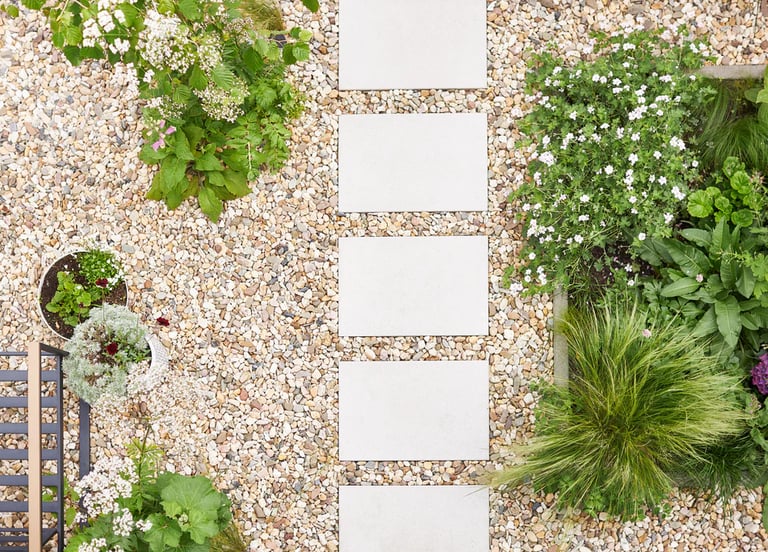 Aerial view of decorative river gravel walkway with square modern pavers and garden planters.