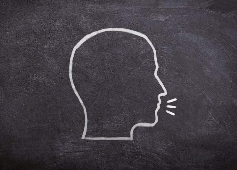 Un visage dessiné de profil sur un tableau noir, avec une bulle de dialogue