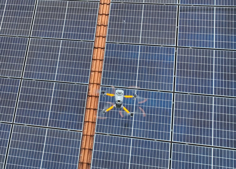 A thermal imaging drone flying over a residential solar panel array for maintenance inspection.