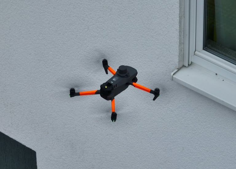 A thermal DJI drone scan the side of a white stucco building wall.