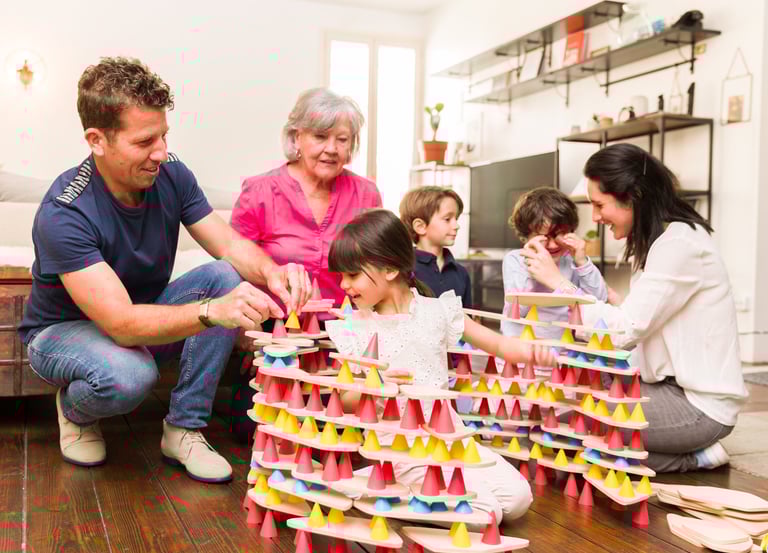 Family creating a structure from colorful silicone cones and wooden tables in the room