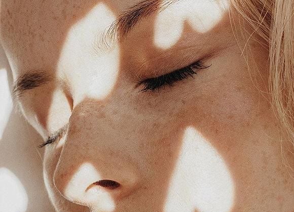 une femme détendue avec des lumières en forme de coeur sur son visage au soleil
