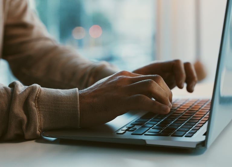 Person with beige sweater typing on a laptop symbolizing meaningful obituary services.