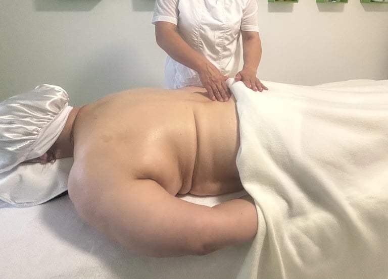 Séance de massage bien-être : une praticienne effectue un massage du dos sur une personne allongée