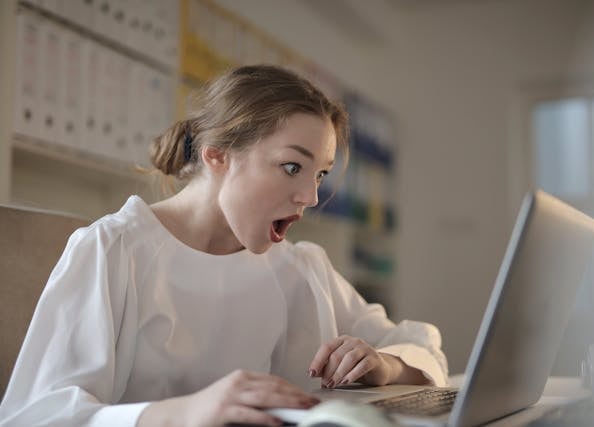 mulher usando laptop com expressao de surpresa
