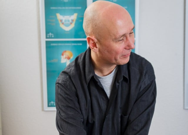 a man in a black shirt and jeans sitting on a table