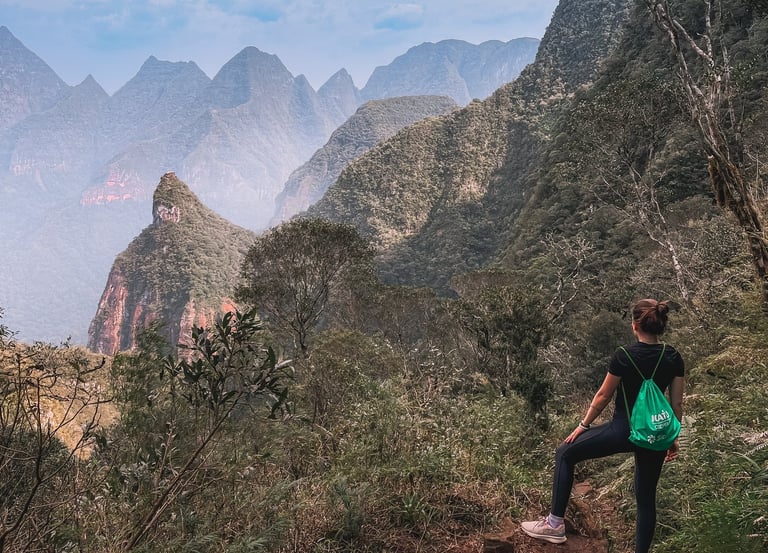 Uma pessoa de costas olhando para os vales no topo da montanha.