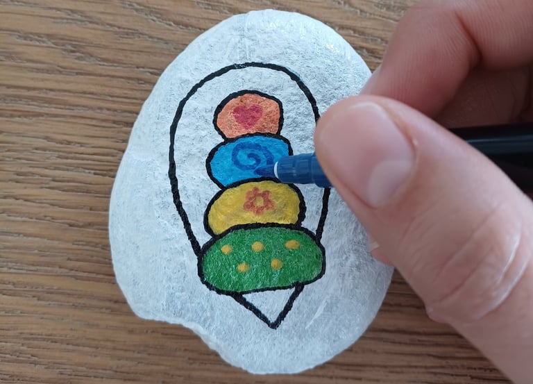 a person's hand holding a pen and drawing on a rock