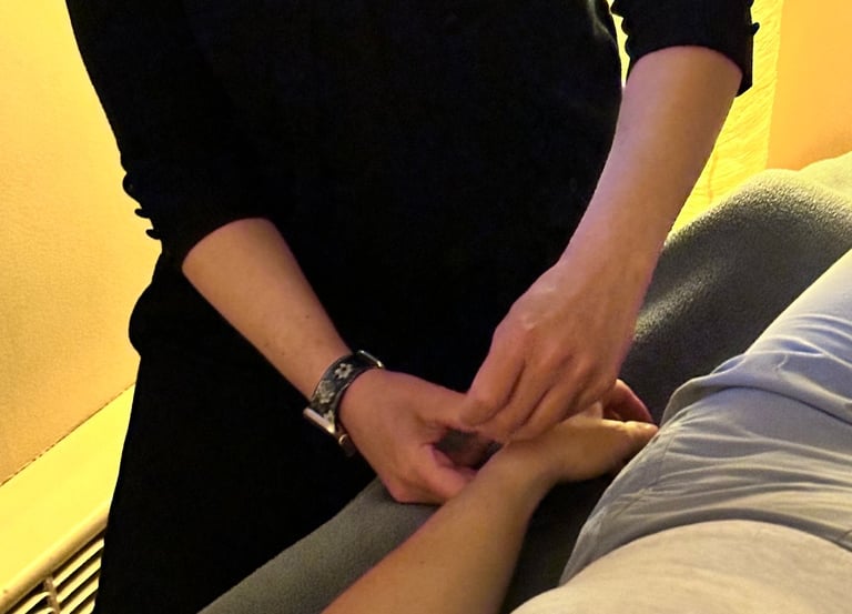 Acupuncturist inserting needle into patient’s wrist on acupuncture table. 