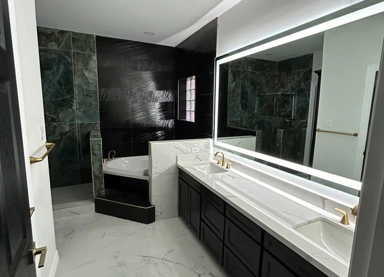 Modern master bathroom with white marble floors, a double vanity, and a black accent tile shower.