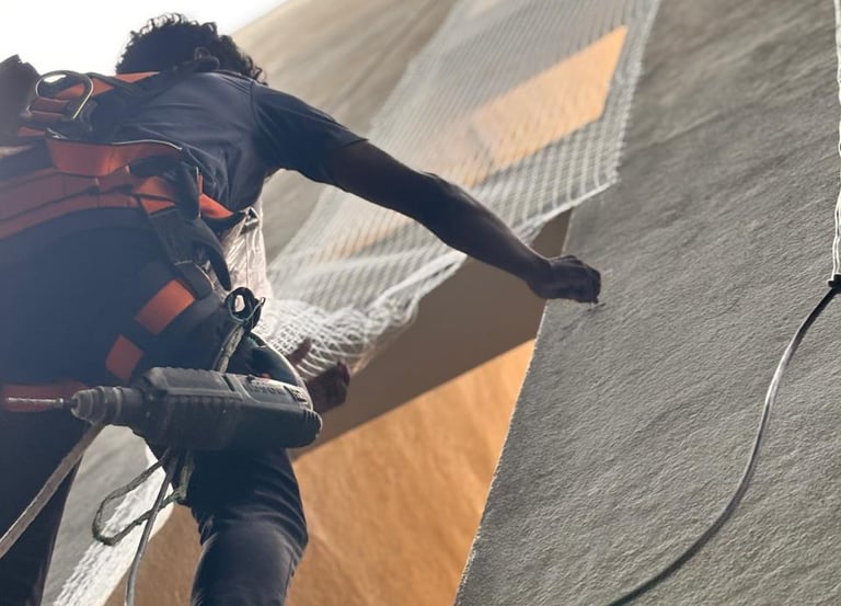 A technician carefully fitting a sturdy pigeon net on a modern apartment balcony in Bellandur.