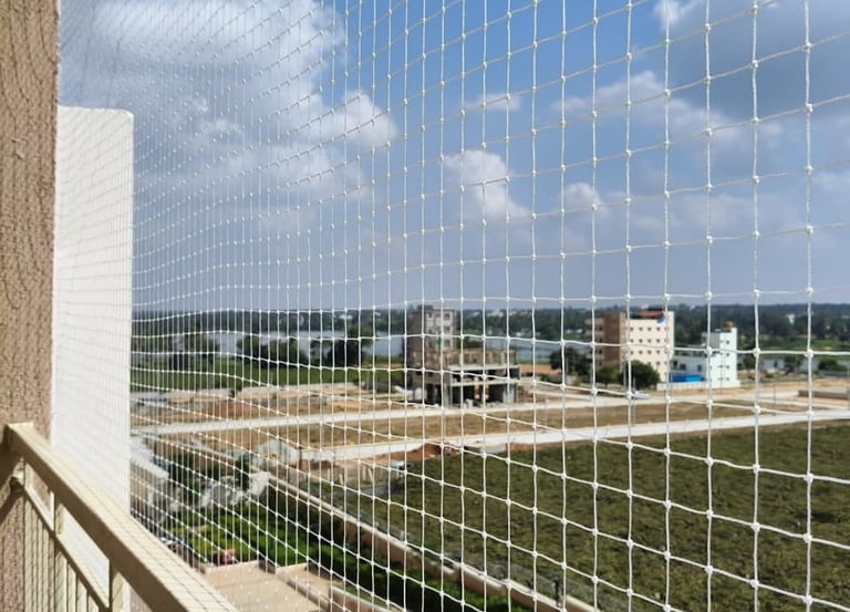 A close-up of a securely installed pigeon net on a sunny Chennai balcony.