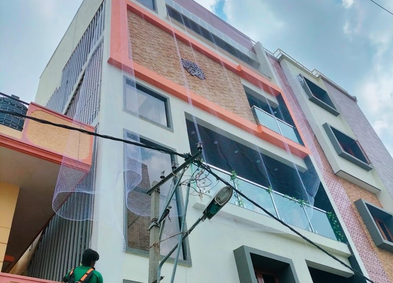 A technician carefully installing a sturdy safety net on a residential balcony in Velacherry.