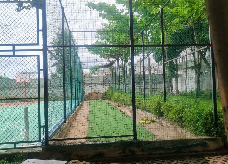 A skilled technician fitting a durable cricket net on a sunny terrace.
