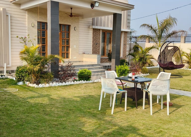 Modern luxury PG exterior featuring a green lawn with a patio dining set and a hanging egg chair.