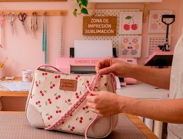 Handmade cream shoulder bag with cherry pattern being crafted in a pink sublimation studio.
