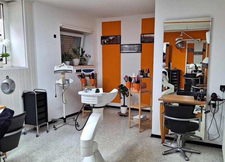 Modern hair salon interior with orange accents, styling stations, and professional shampoo sinks.