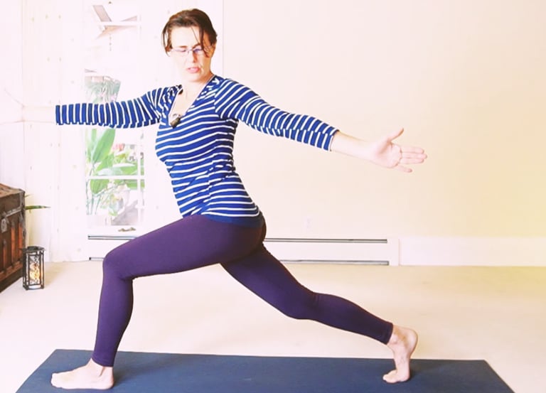 Woman practicing a yoga spinal twist in a crescent lunge pose on a blue mat.