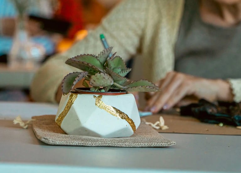 a woman sitting at a table with a plant in a potted potted with