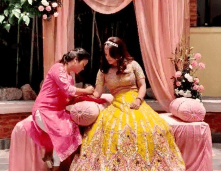 Henna artist doing henna on groom"s hand during mehendi ceremony