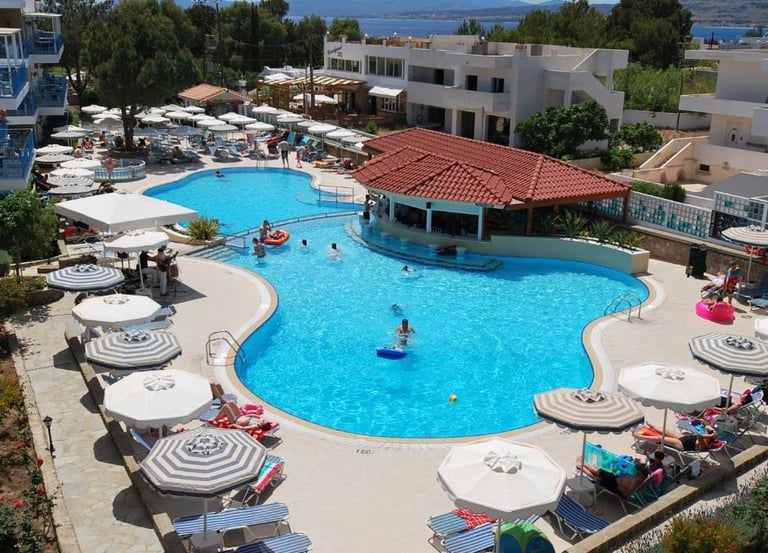 Luxury resort swimming pool with a swim-up bar, white umbrellas, and lounge chairs for summer vacation.