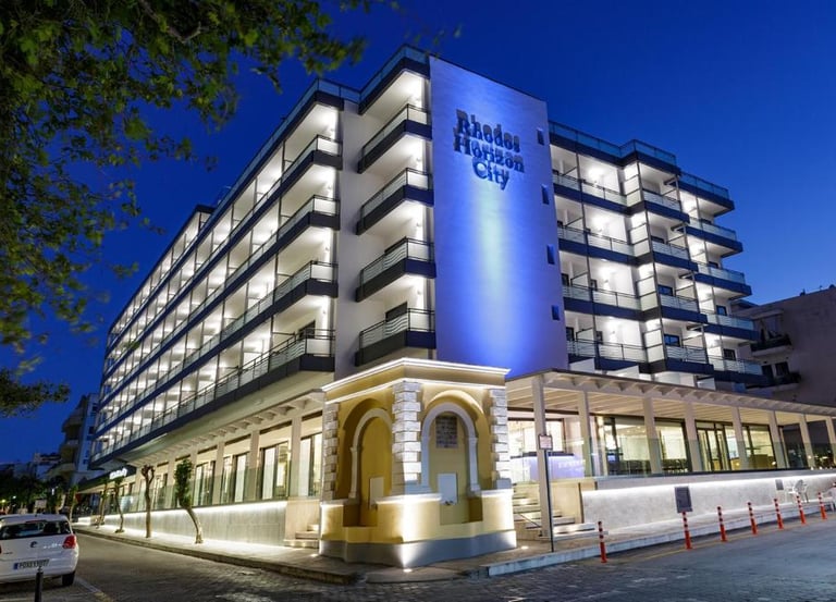 Modern facade of Rhodes Horizon City hotel with illuminated balconies at twilight in Greece.