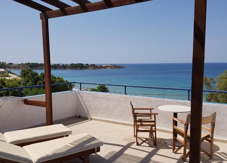 Sunny hotel balcony with lounge chairs and panoramic Mediterranean Sea views in Cyprus.