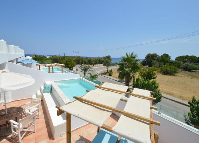 Luxury hotel balcony with a private plunge pool, patio furniture, and scenic ocean views in a tropical resort.