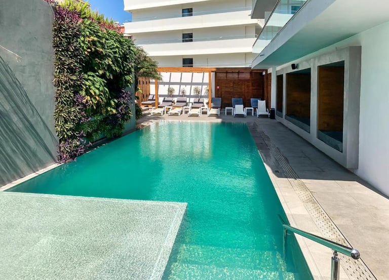Luxury outdoor swimming pool at a modern hotel with a vertical garden wall and lounge chairs.