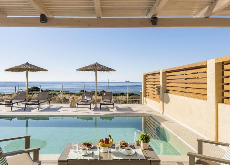 Luxury villa terrace with private infinity pool overlooking the ocean with lounge chairs.