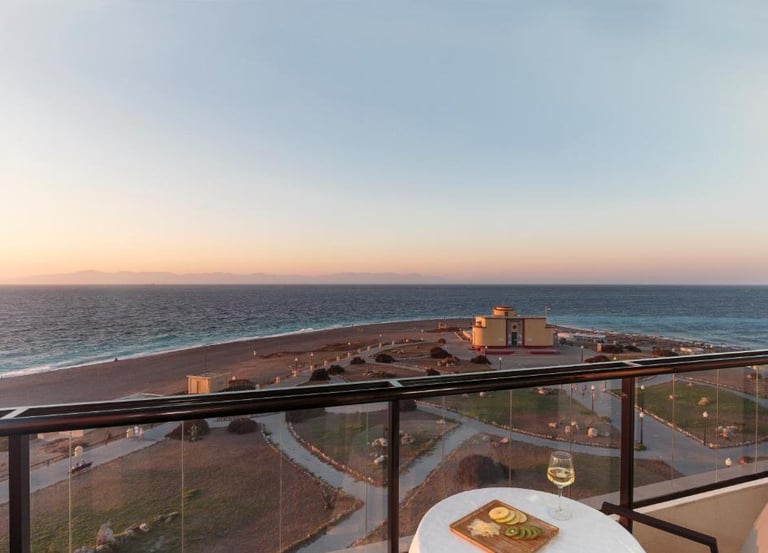 A sunset view of Rhodes beach and the aquarium from a luxury hotel balcony with wine and cheese.