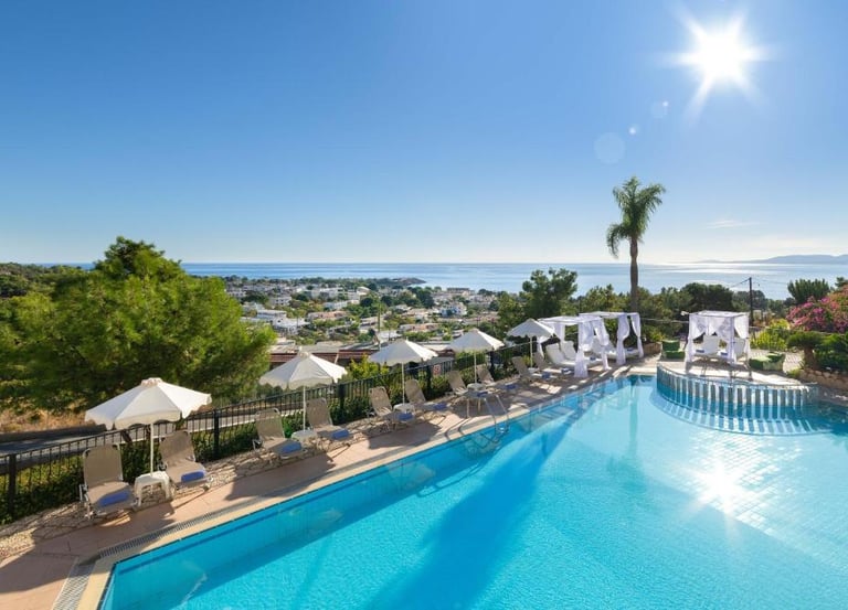 Luxury hotel swimming pool with sun loungers and ocean views under a bright sunny sky.