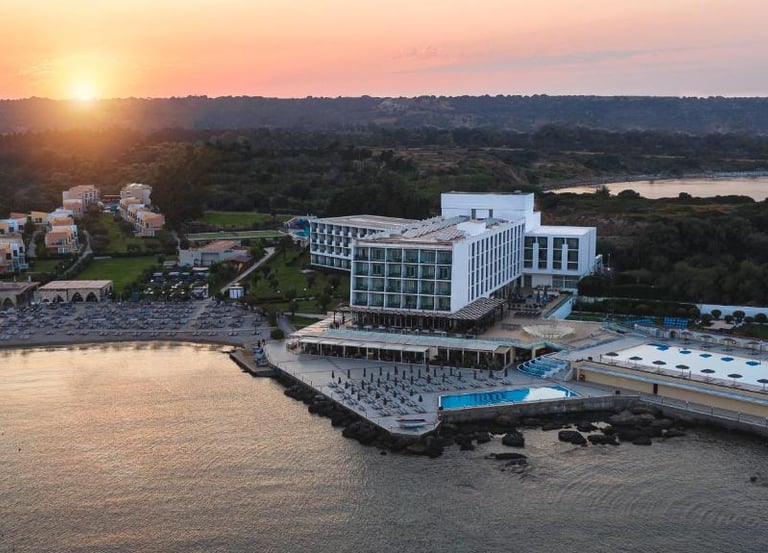 Aerial view of a luxury beachfront resort with a swimming pool at sunset.