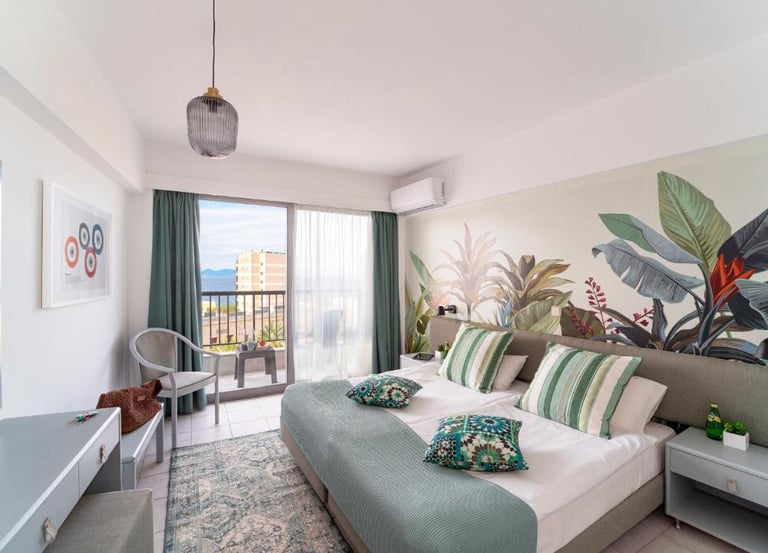 Modern hotel room with a botanical wall mural, private balcony, and tropical decor.